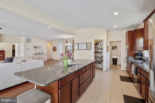 kitchen with a center island, a sink, open floor plan, light tile patterned floors, and recessed lighting
