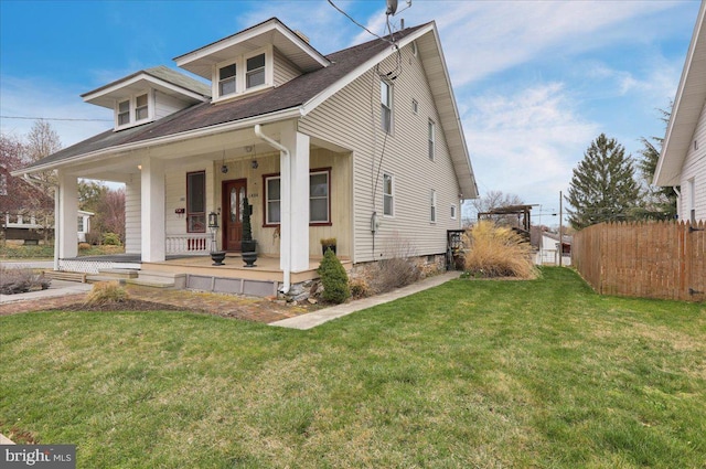 bungalow featuring a front yard, roof with shingles, fence, and covered porch