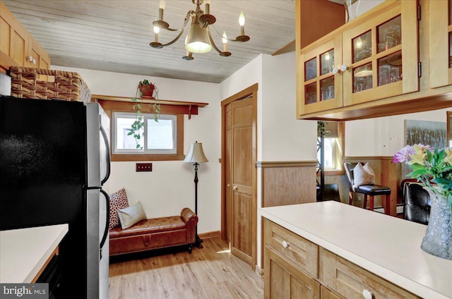 kitchen with light countertops, freestanding refrigerator, a notable chandelier, and light wood-style floors
