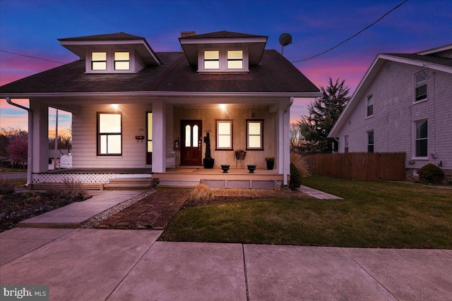 view of front of home featuring a front yard, fence, and covered porch