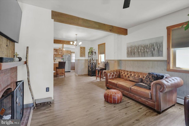 living area featuring wooden walls, beam ceiling, wood finished floors, a wainscoted wall, and a baseboard heating unit