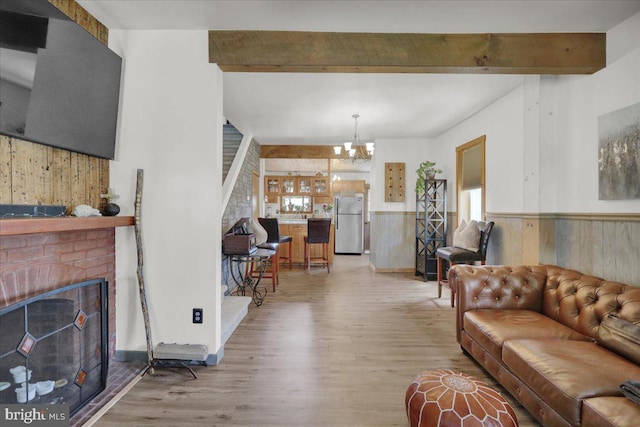 living area featuring an inviting chandelier, light wood finished floors, wood walls, and beamed ceiling