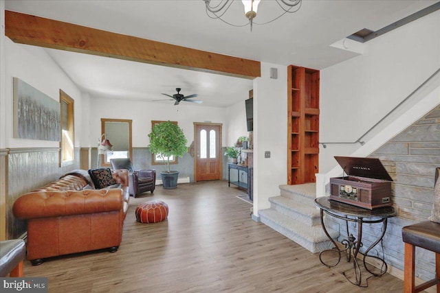 living area with stairs, ceiling fan, beamed ceiling, and wood finished floors
