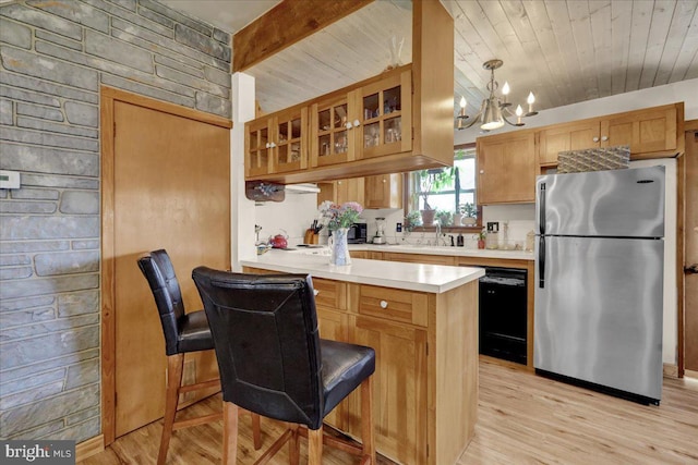 kitchen with a chandelier, a peninsula, light countertops, freestanding refrigerator, and dishwasher