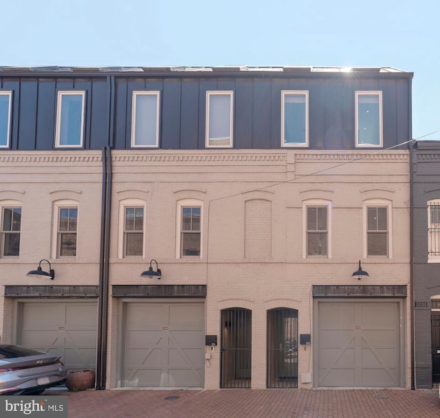 townhome / multi-family property featuring brick siding, a garage, and driveway
