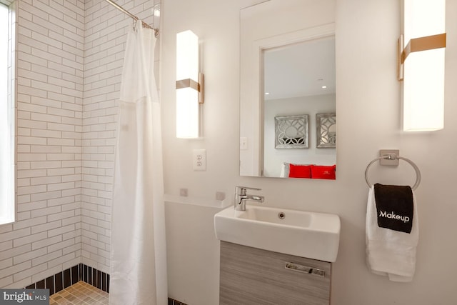 bathroom featuring a tile shower and a sink