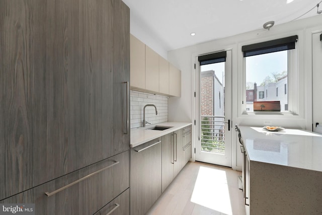 kitchen featuring decorative backsplash, modern cabinets, a sink, light countertops, and light wood-style floors