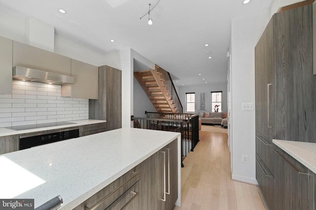 kitchen featuring under cabinet range hood, black electric cooktop, modern cabinets, and oven