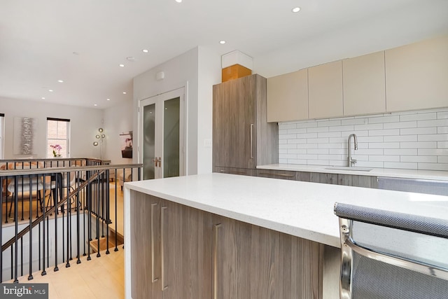 kitchen with a sink, light wood-style floors, recessed lighting, tasteful backsplash, and modern cabinets