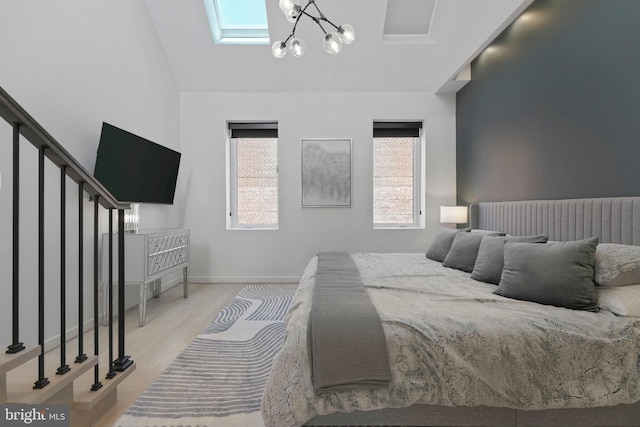 bedroom with light wood-type flooring, baseboards, vaulted ceiling, and an inviting chandelier