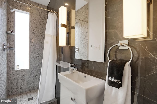 bathroom featuring decorative backsplash, tile walls, a shower stall, and a sink