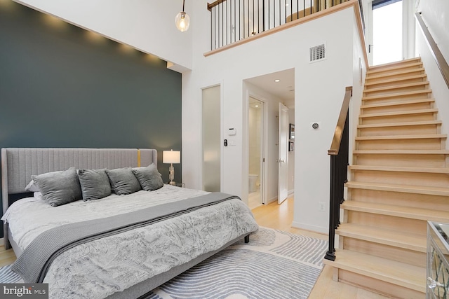 bedroom featuring a towering ceiling, visible vents, wood finished floors, baseboards, and recessed lighting