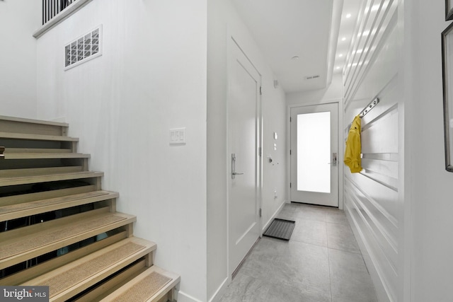 hall with baseboards, stairs, and visible vents