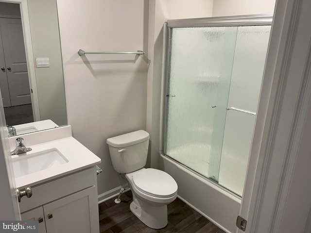 bathroom with baseboards, toilet, enclosed tub / shower combo, vanity, and wood finished floors