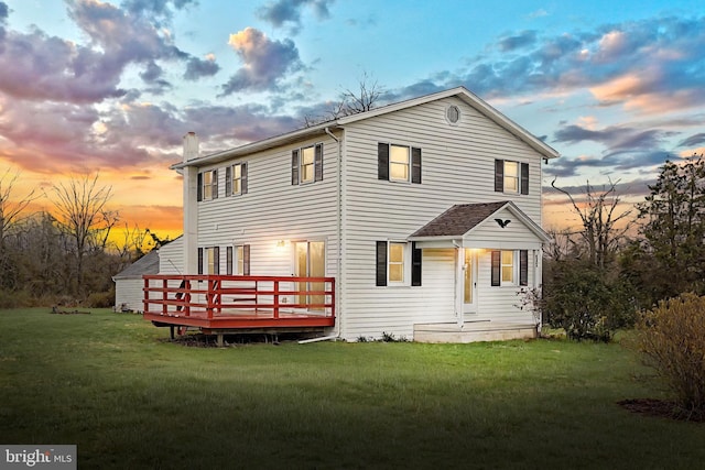 rear view of house with a deck and a lawn