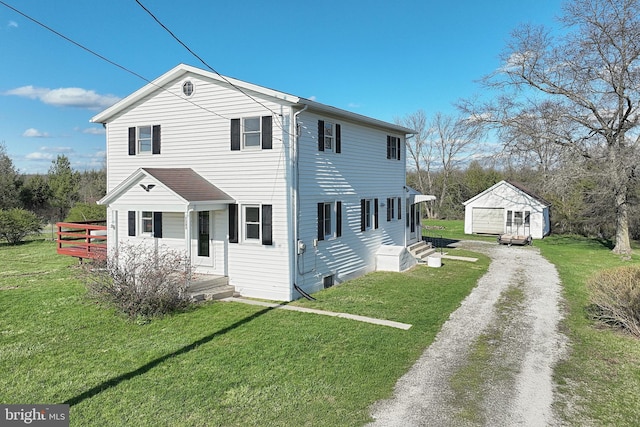 back of property with a yard, driveway, and an outbuilding