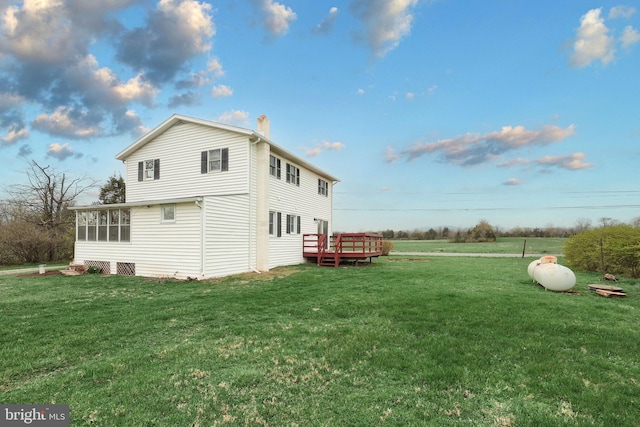 view of side of property with a chimney, a wooden deck, and a yard