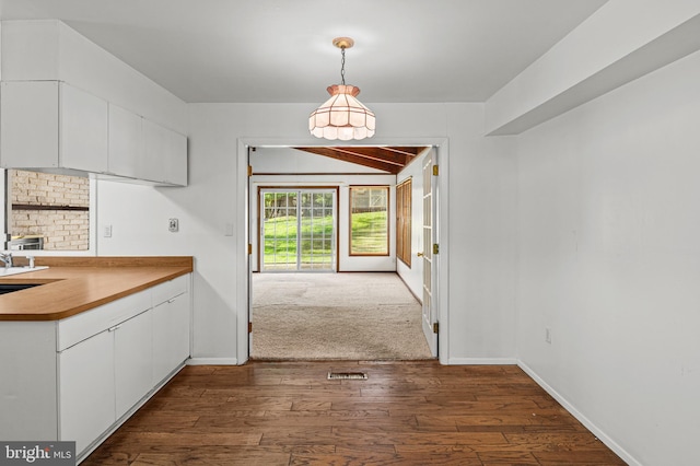 interior space featuring hanging light fixtures, white cabinets, baseboards, and dark wood finished floors