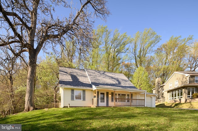 view of front of house featuring a shingled roof, a front yard, and fence