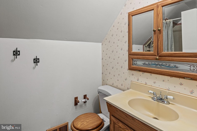 full bathroom featuring toilet, lofted ceiling, and wallpapered walls