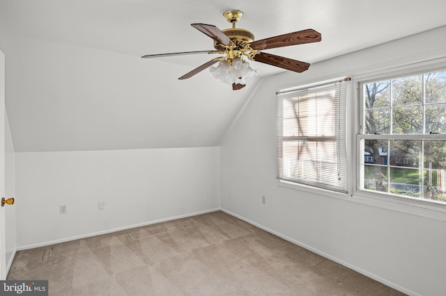 additional living space featuring baseboards, plenty of natural light, light colored carpet, and vaulted ceiling