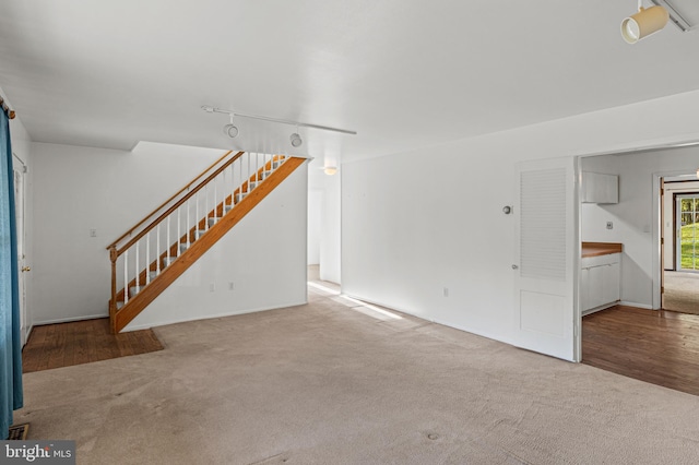 unfurnished living room with carpet floors and stairs
