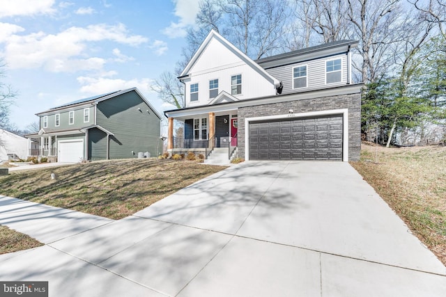 view of front of house featuring an attached garage, concrete driveway, stone siding, and a porch