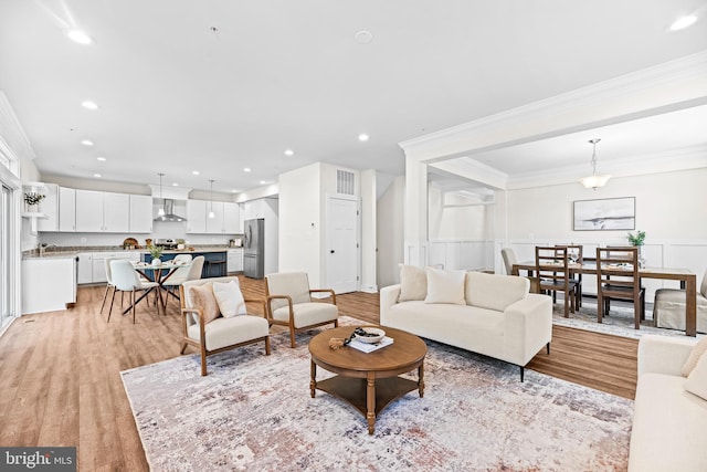 living area with crown molding, visible vents, light wood finished floors, and recessed lighting