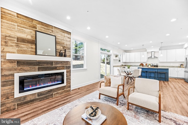 living area featuring baseboards, ornamental molding, light wood-type flooring, a fireplace, and recessed lighting