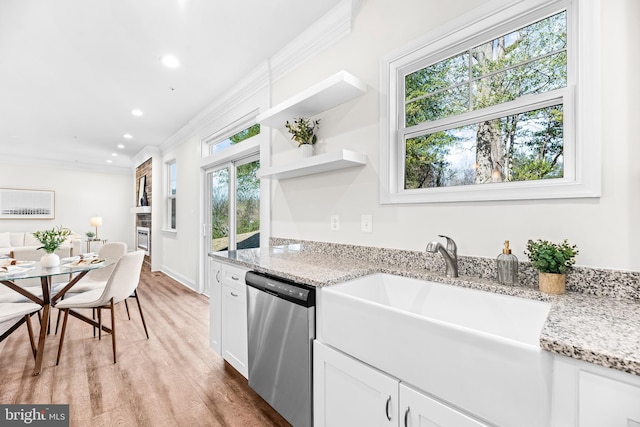 kitchen featuring light wood-style floors, stainless steel dishwasher, white cabinetry, ornamental molding, and light stone counters