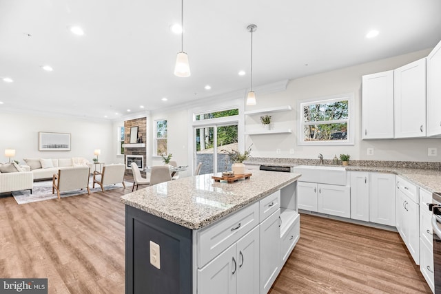 kitchen with open floor plan, light wood-style flooring, a center island, white cabinets, and a sink