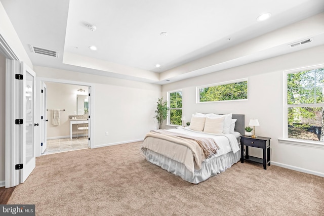 bedroom with visible vents, multiple windows, and light carpet