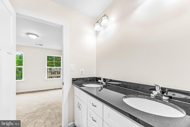 full bathroom with a sink, visible vents, baseboards, and double vanity