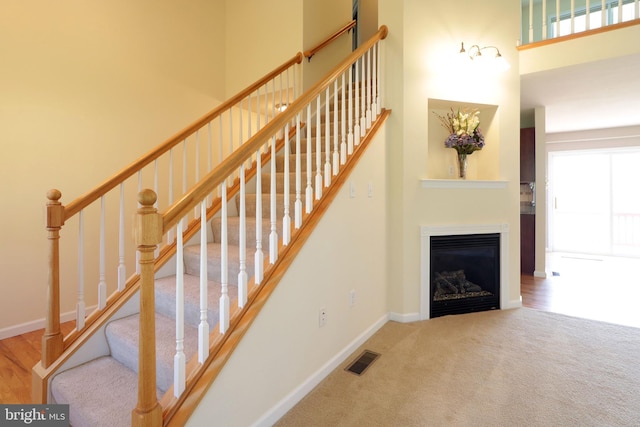 142 Faust Cir, Bellefonte, PA 16823 - staircase featuring carpet flooring, a glass covered fireplace, baseboards, a towering ceiling, and visible vents