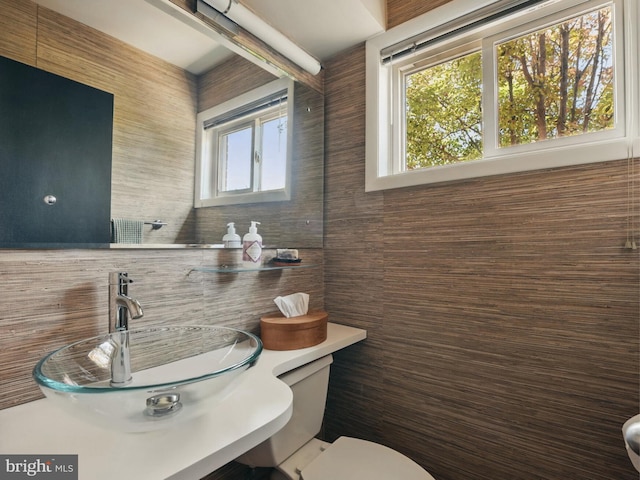 bathroom featuring a sink, tile walls, decorative backsplash, and toilet