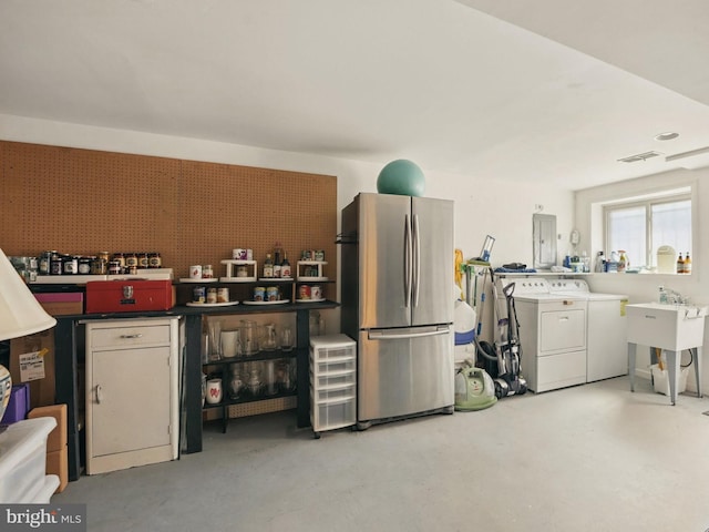 kitchen featuring visible vents, freestanding refrigerator, washer and clothes dryer, electric panel, and concrete floors