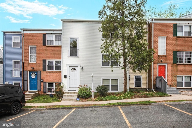 townhome / multi-family property featuring uncovered parking and brick siding