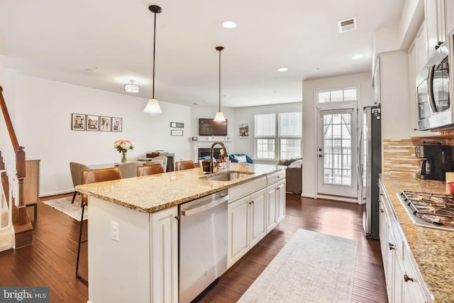 kitchen featuring a sink, a kitchen breakfast bar, a center island with sink, stainless steel appliances, and white cabinets