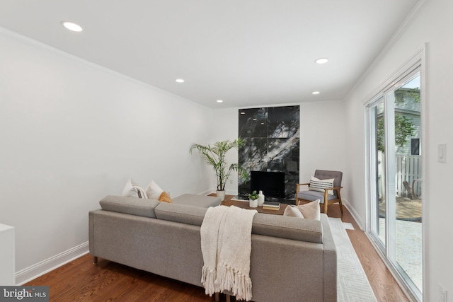 living area with baseboards, wood finished floors, recessed lighting, and crown molding