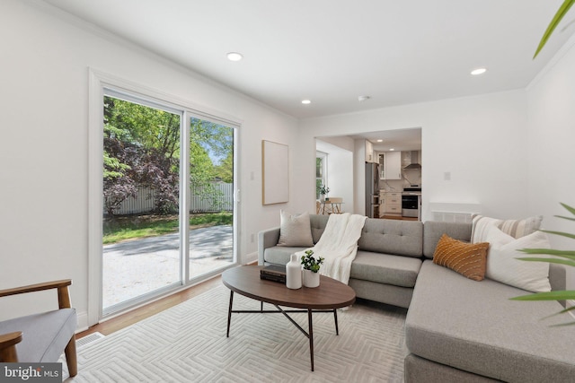 living room featuring baseboards, crown molding, light wood-style floors, and recessed lighting