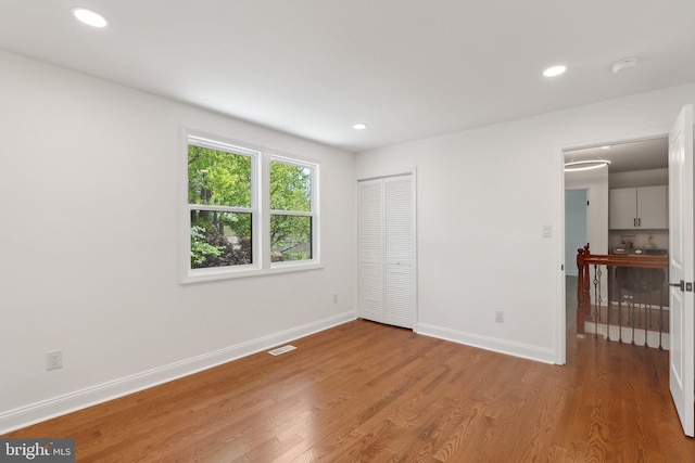unfurnished bedroom featuring recessed lighting, visible vents, a closet, baseboards, and light wood-style flooring