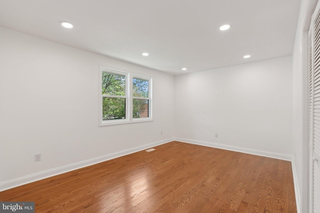 unfurnished room featuring recessed lighting, wood finished floors, and baseboards