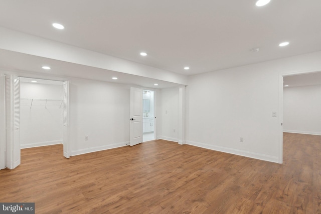 basement featuring baseboards, wood finished floors, and recessed lighting