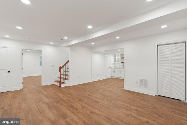 below grade area featuring stairs, wood finished floors, visible vents, and recessed lighting