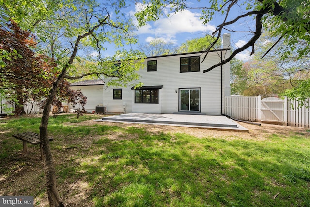 back of house with a gate, central AC, a chimney, fence, and a lawn
