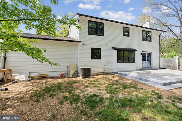 rear view of house with fence, a chimney, central air condition unit, and a patio