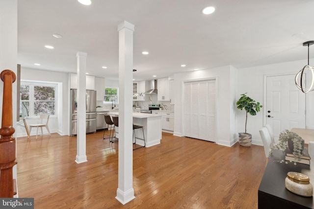 living room with light wood-type flooring, decorative columns, baseboards, and recessed lighting