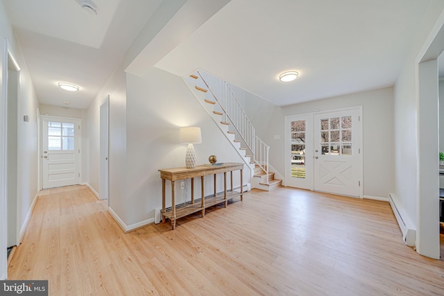foyer with stairs, baseboard heating, baseboards, and wood finished floors