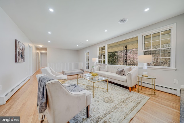 living area featuring baseboard heating, a baseboard heating unit, visible vents, and wood finished floors