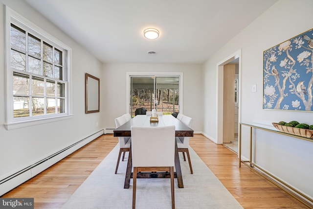dining space featuring light wood-type flooring, a baseboard heating unit, and visible vents